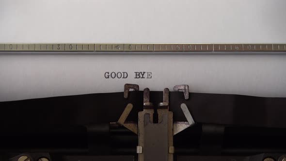 Typing phrase GOOD BYE on retro typewriter. Close up.