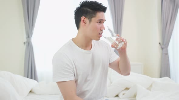 Portrait of Asian active strong man holding clean water in bedroom.