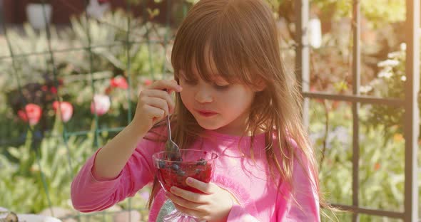 Cute Little 6 or 7 Years Old Girl Eating Fruit Dessert Jelly in Summer Garden