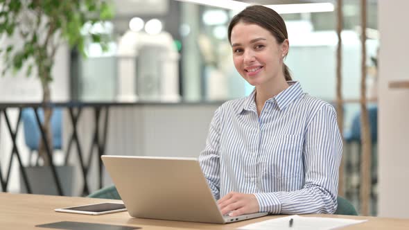 Cheerful Young Woman with Laptop Smiling at Camera in Office 