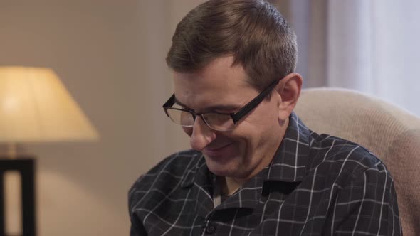 Close-up Portrait of Happy Caucasian Middle Aged Man in Eyeglasses Looking at Something Down and