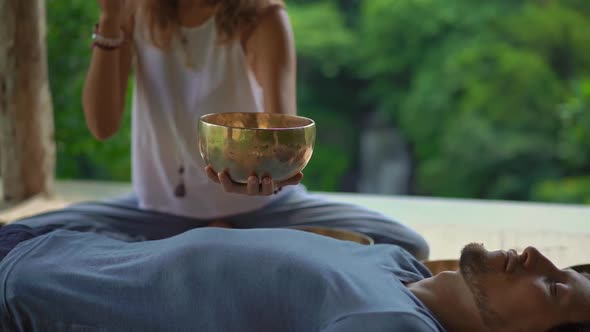 Superslowmotion Shot of a Woman Master of Asian Sacred Medicine Performs Tibetan Bowls Healing