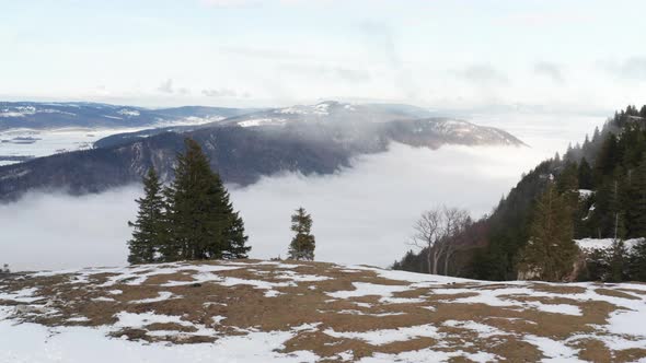 Flying over mountain ridge, revealing beautiful valley with low hanging clouds