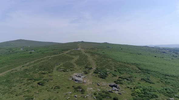 Wide shot aerial tracking forward over the wide expanse of Dartmoor, tors, grassy moorland and rocky