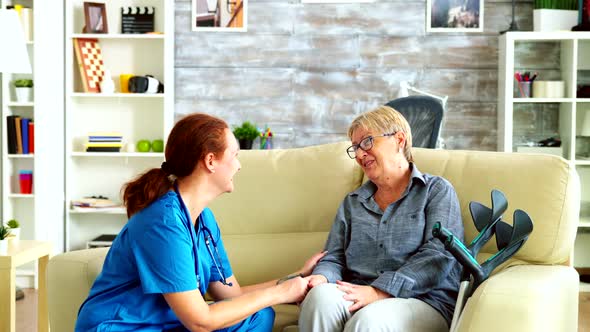 Female Nurse Holding Old Woman Hand in Nursing Home