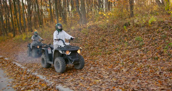 A Young Couple Rides an ATV Offroad in the Autumn Forest