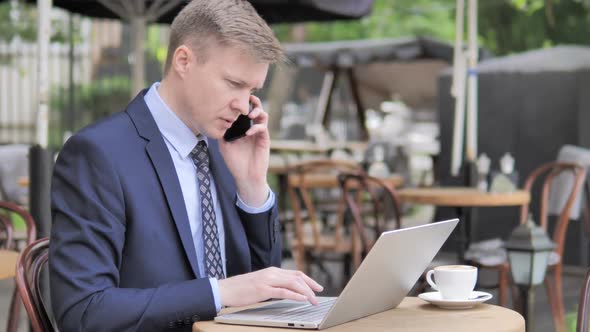 Businessman Talking on Phone While Sitting in Outdoor Cafe