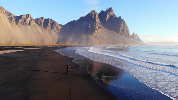 Anonymous person walking near waving sea