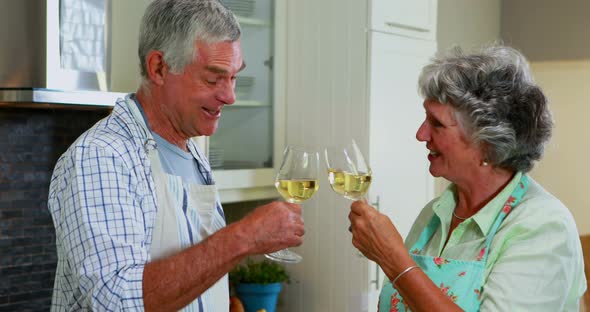 Senior couple interacting while having wine in kitchen 4k