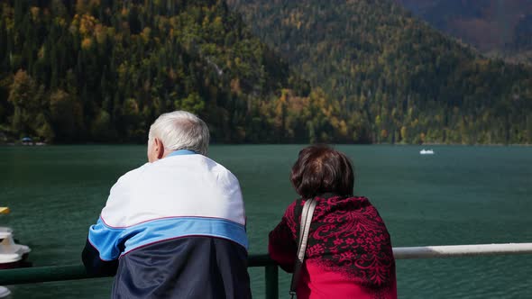 Family of Old Travelers Watching Sailing Boats on Windy Mountain Lake Together