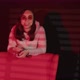Young Woman in Glasses Standing Behind Armchair in Dark Room with Falling Red Light and Shadow - VideoHive Item for Sale