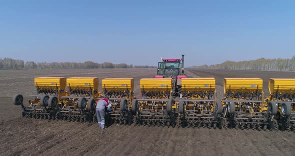 Farmer in the Field Checks and Repairs the Seeder