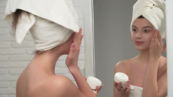 Woman in Towel Putting Cream on Face