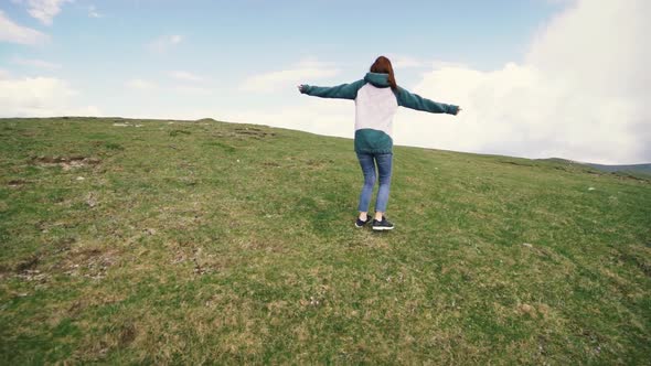 A Young Woman Hiker Running and Spinning on Top of a Mountain