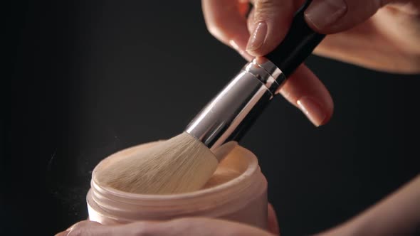 Closeup of Female Hands Holding and Shaking Face Powder Off a Brush