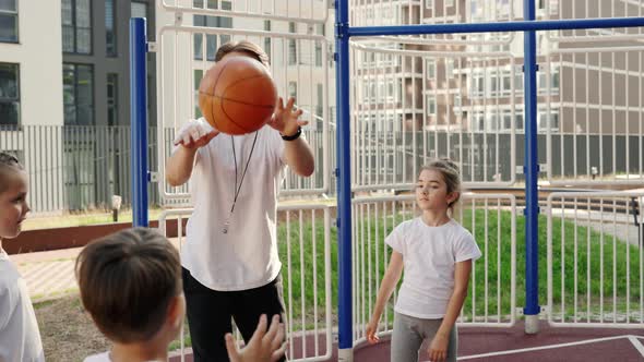 School Coach Mentoring Kids How to Catch and Throw the Ball on Basketball Court Outdoor