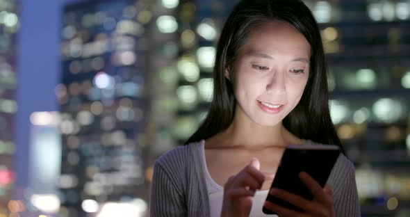 Business woman use of mobile phone in city at night