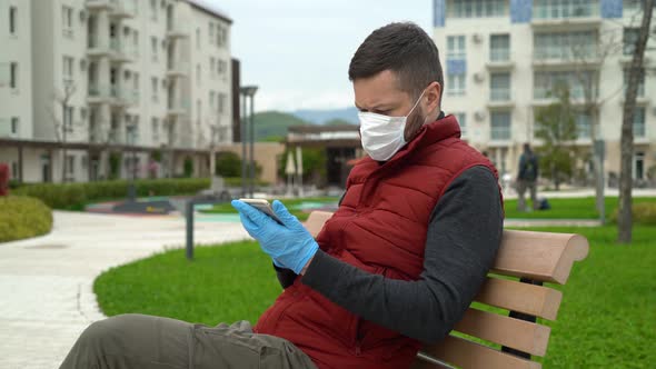 Man in a Mask Uses a Smartphone