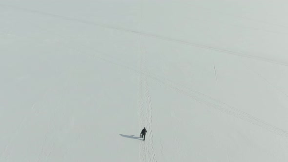 man walks in the snow leaving footprints behind