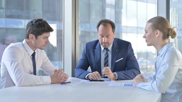 Middle Aged Businessman Having Talk on Documents with Assistants on Office Table