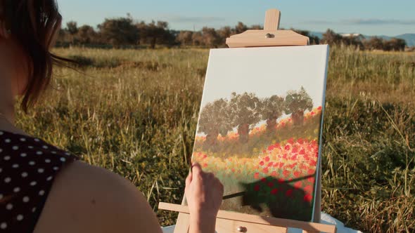 Young girl paints the picture on canvas in the countryside