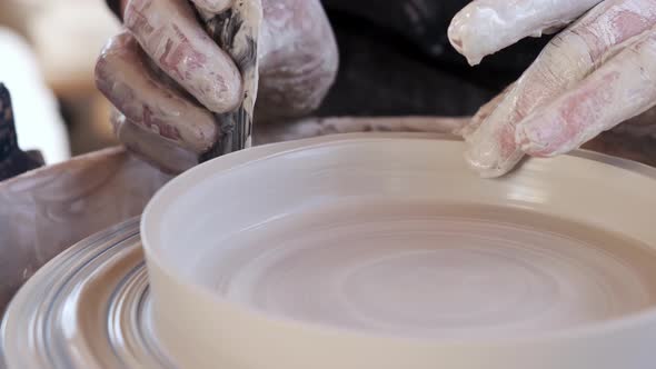 Crop woman sculpturing pot with clay