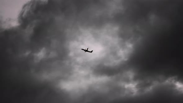 Airplane Flying Though Dark Clouds In Sky Above Akueyri