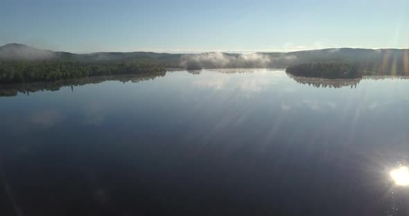 Aerial shot flying over a forest and calm watered lake in northern Ontario Canada.