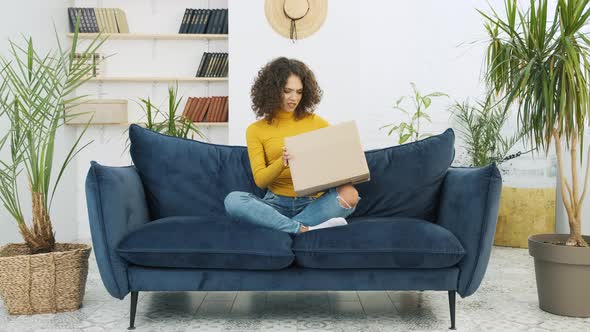 Disappointed Young Woman Unpacking Huge Carton Box Looking Inside