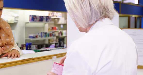 Pharmacist assisting the bottle of drug to customer