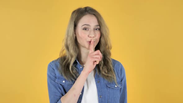 Young Pretty Girl Gesturing Silence Finger on Lips Yellow Background