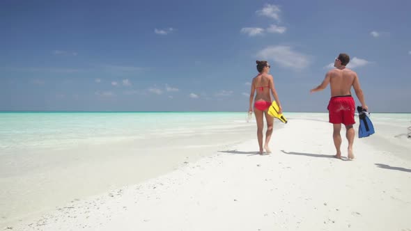 People With Flippers Walking on Sandy Beach