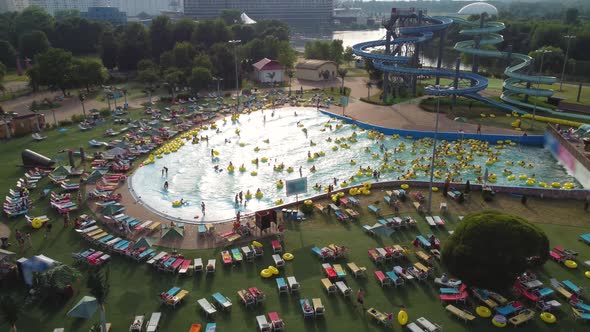 Summer day in the city water park, people have a rest, swim on inflatable rings.