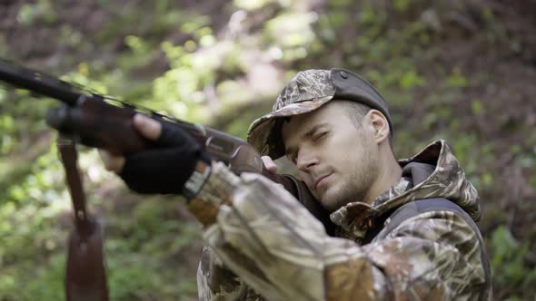 Man Takes Aim While Standing From Hunting Rifle. Man in Comfortable Camouflage Clothes Hunter