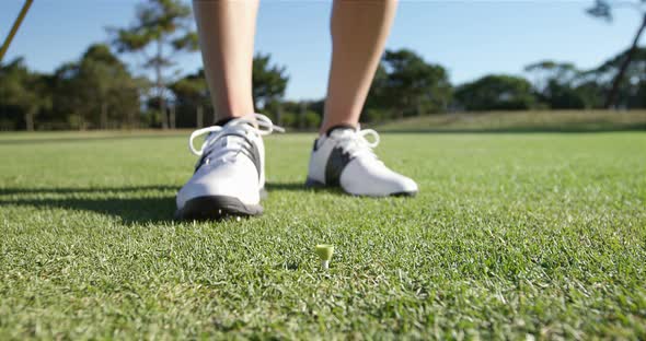 Golfer placing golf ball on tee