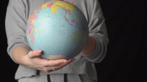 Girl's Hands Twist the Geographic Globe Around Its Axis