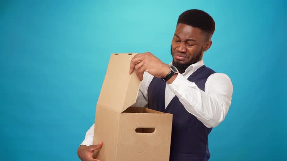 Young African Man Opens Carton Box Dislike What's in It Against Blue Background