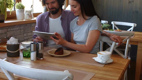 Couple using digital tablet in cafe