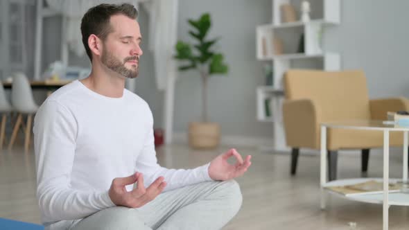 Peaceful Man Meditating on Yoga Mat at Home