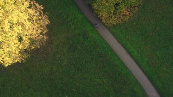 Aerial View on Autumn Park with Cycling Man Along Forest Road