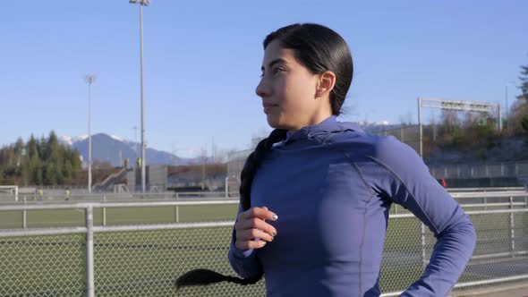 Determined young woman jogging on track and field path, Closeup Follow Shot