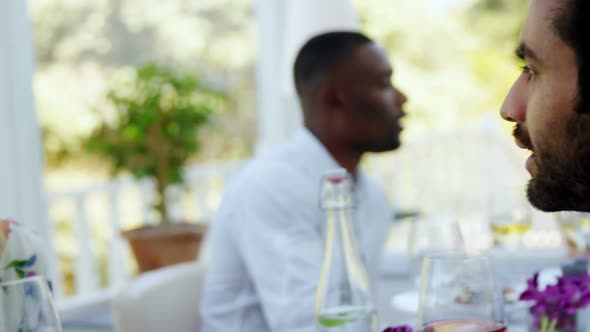 Friends interacting with each other while having glass of wine