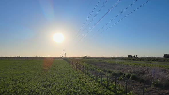 Flight along fence on farm with overhead power lines, the Pampas region, aerial