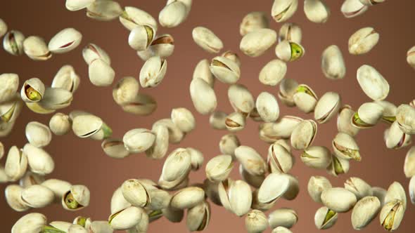 Super Slow Motion Shot of Flying Pistachios After Being Exploded on Brown Background at 1000Fps