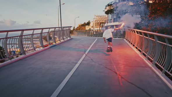 Millennial Guy Skateboarding with Red Signal Fire on Bridge Slow Motion