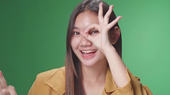 Portrait Of A Happy Asian Woman Showing Okay Gesture To The Camera In The Green Screen Studio