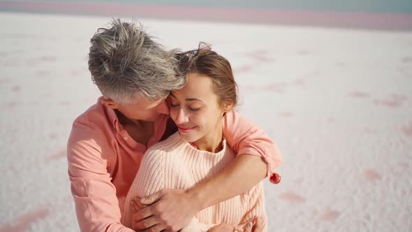 Camera Lifting Along Man and Woman Hugging and Tenderly Touching Each Other on White Desert or Beach
