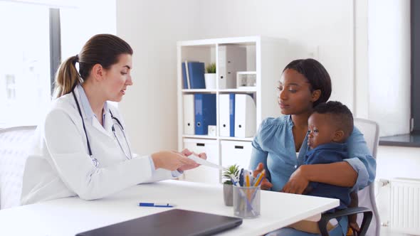 Happy Mother with Baby Son and Doctor at Clinic