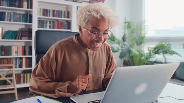 Young African American Woman Rejoices at What He Sees on Laptop Screen
