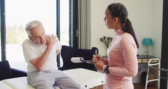 Video of biracial female physiotherapist examining caucasian senior man